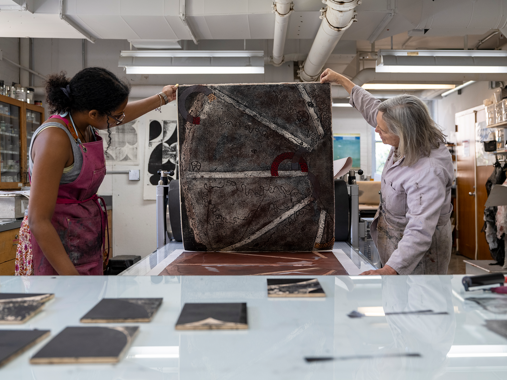 Student and teacher holding up corners of a new print