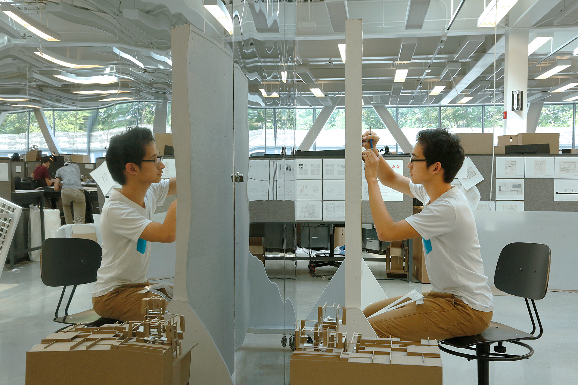 Student working in a pinup board reflected by a mirrored wall