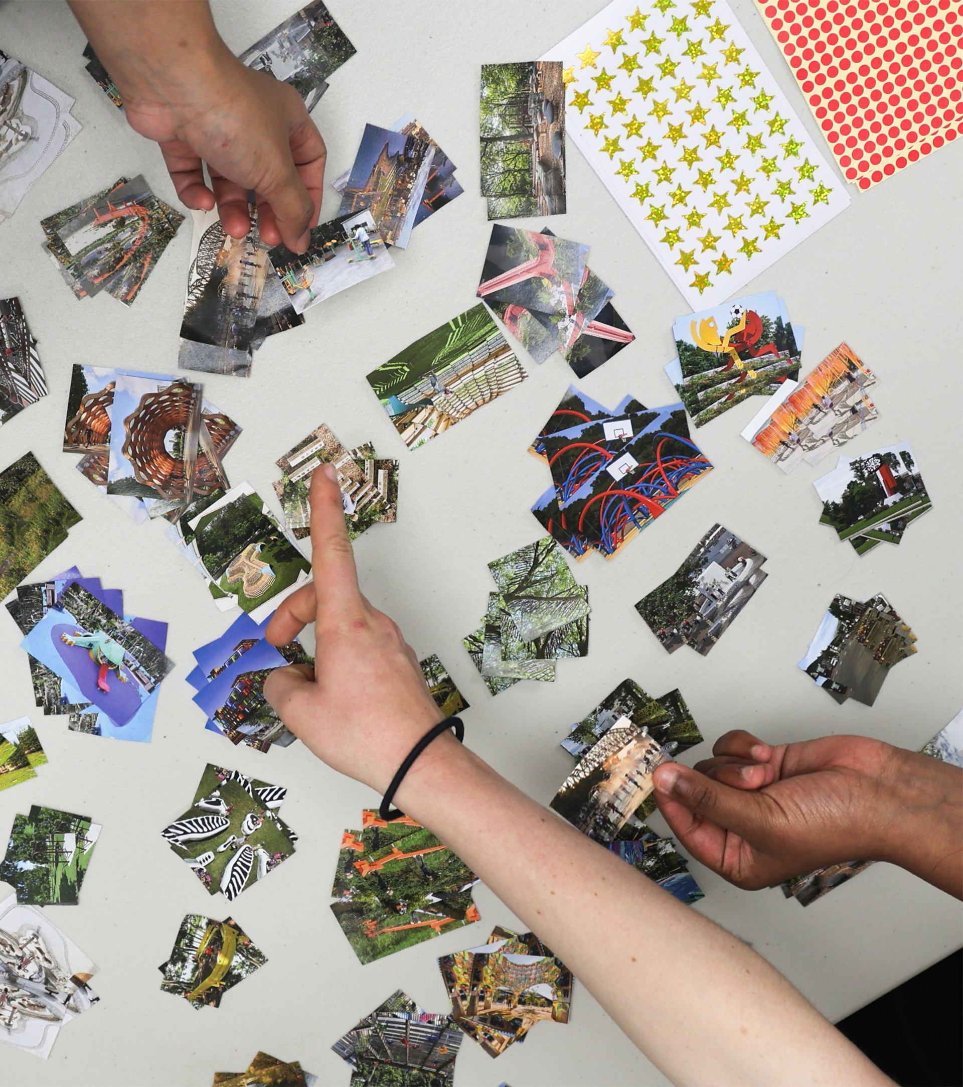 Small images spread across a table with hands point above