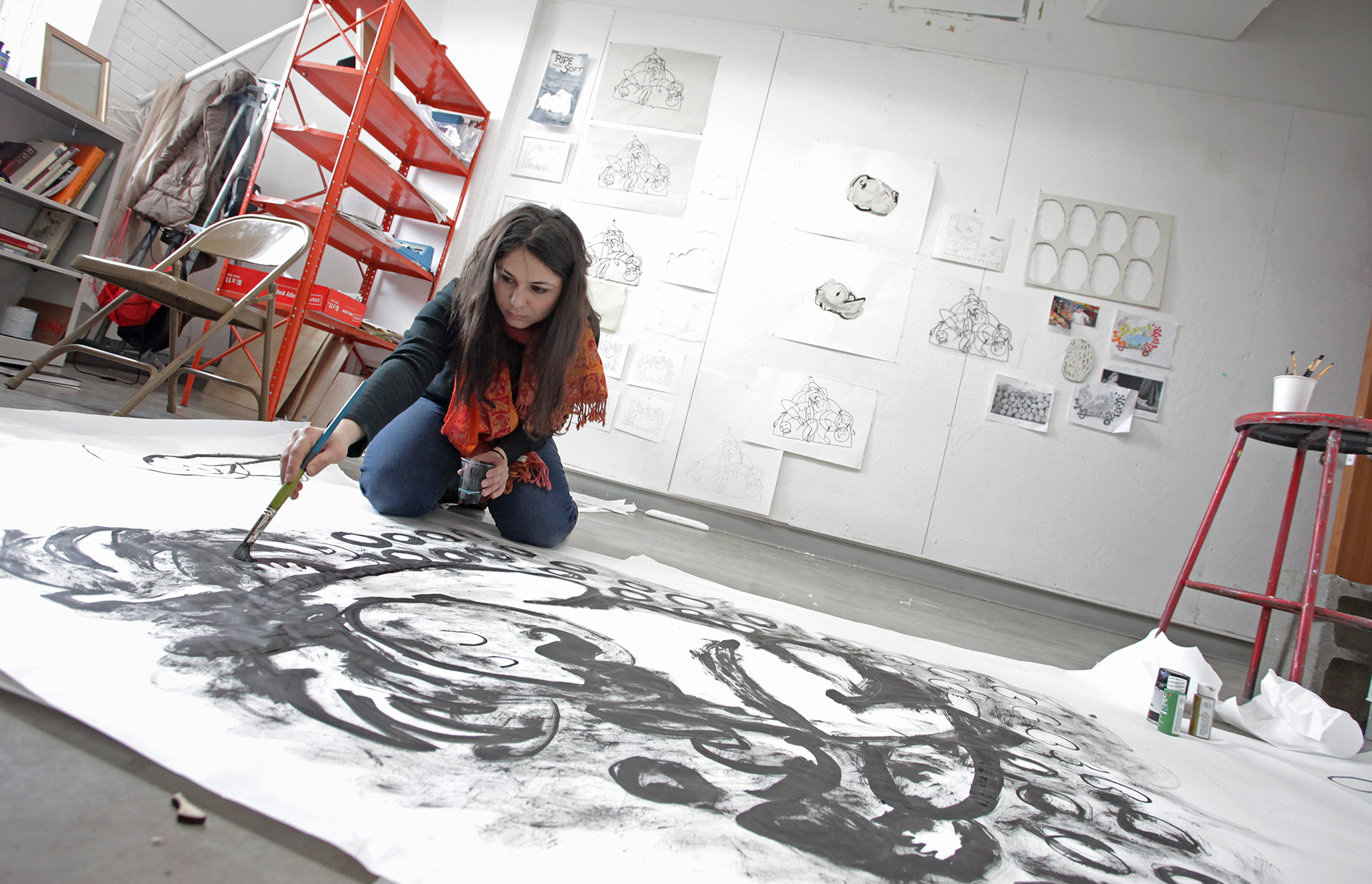Woman painting on a large sheet of paper on the floor