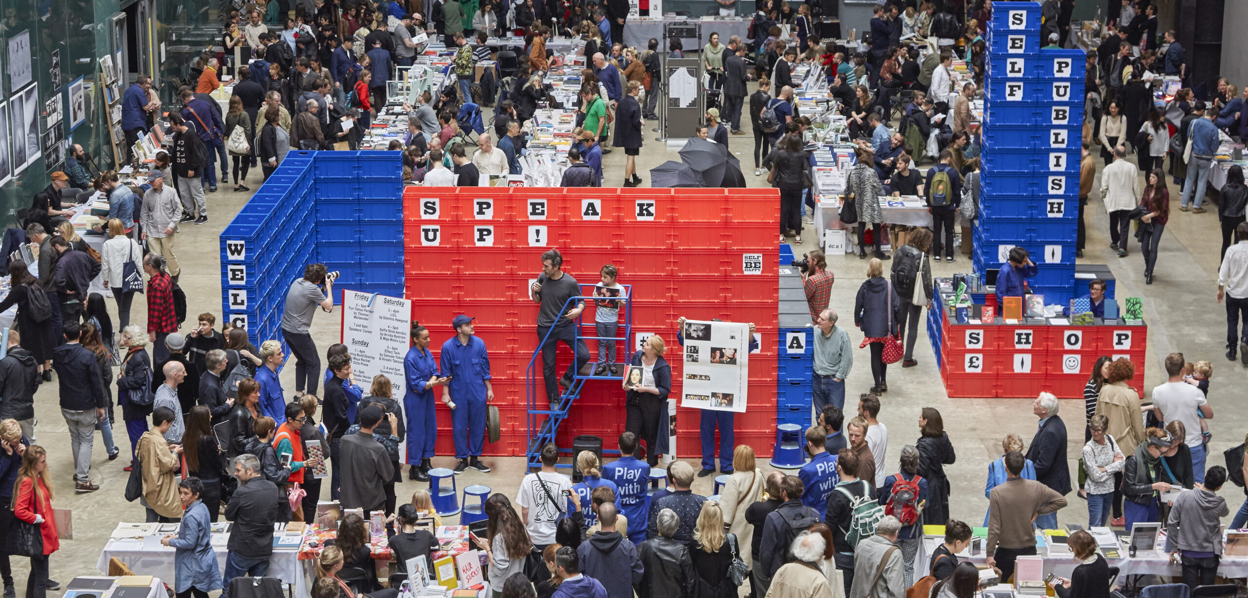 a crowded large room with red and blue stands