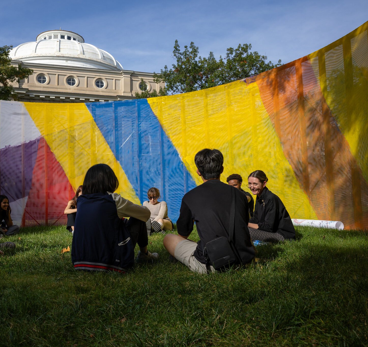 Students and professor seated in a circle outside