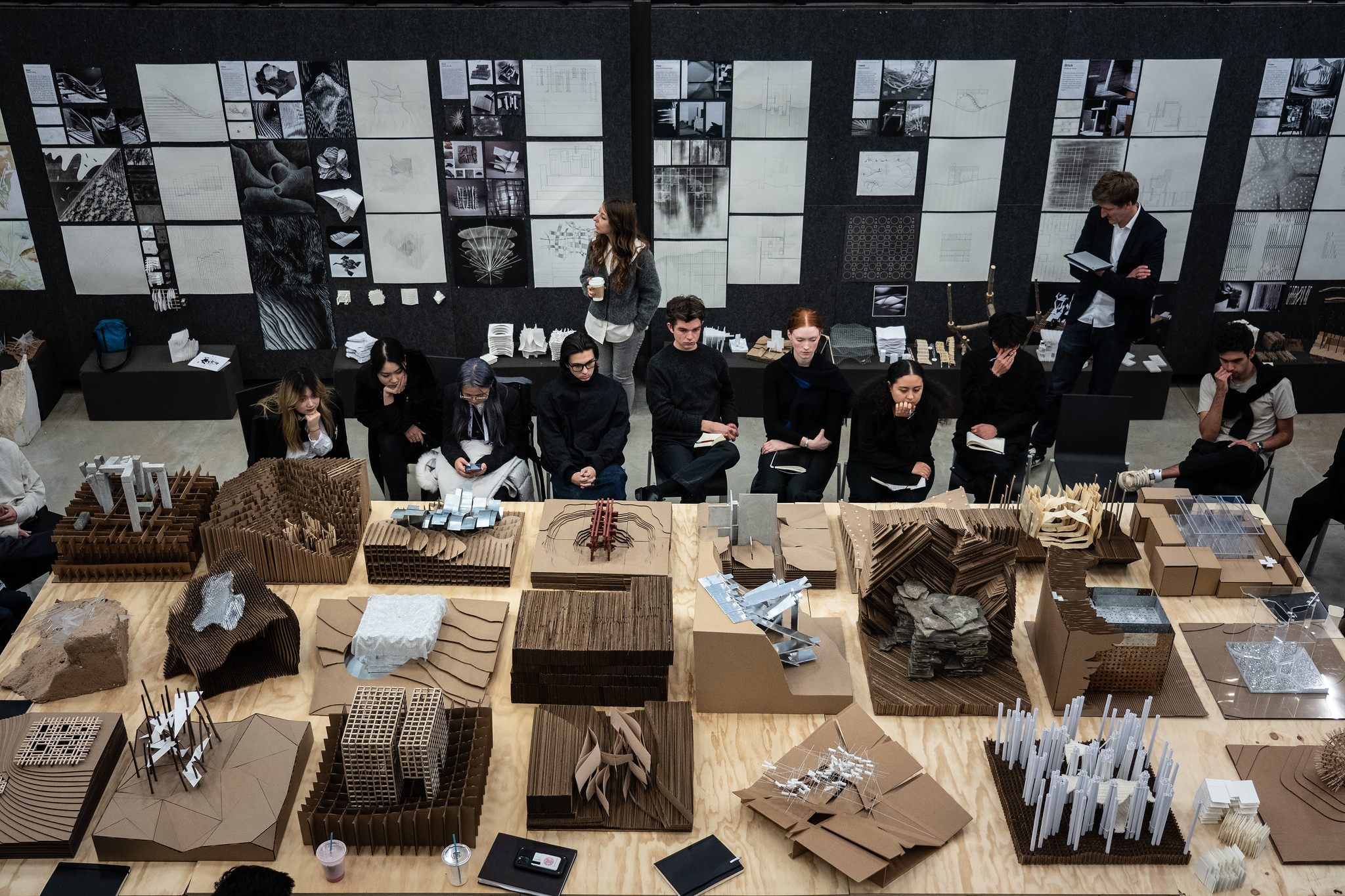 Students seated at a table displaying many architectural models