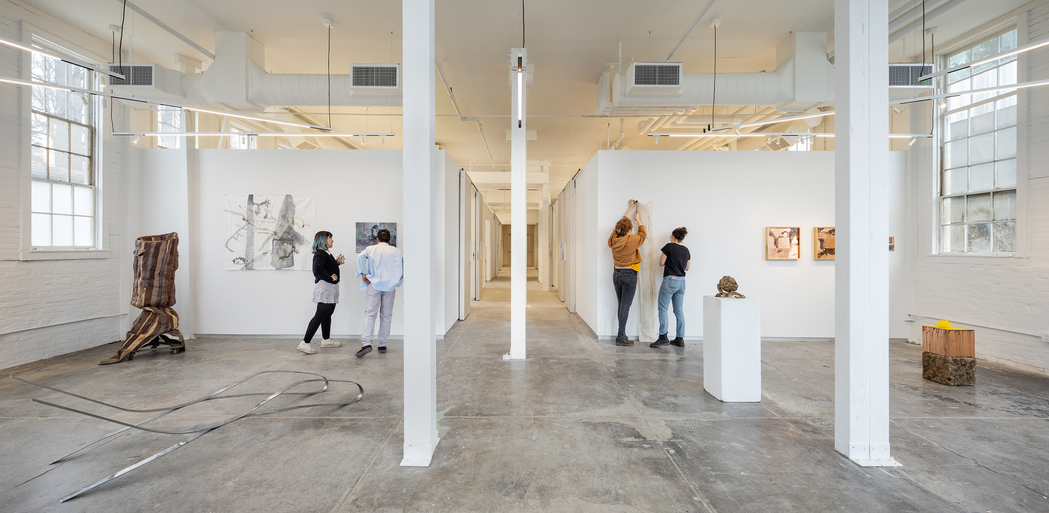 students putting up work in a bright gallery space