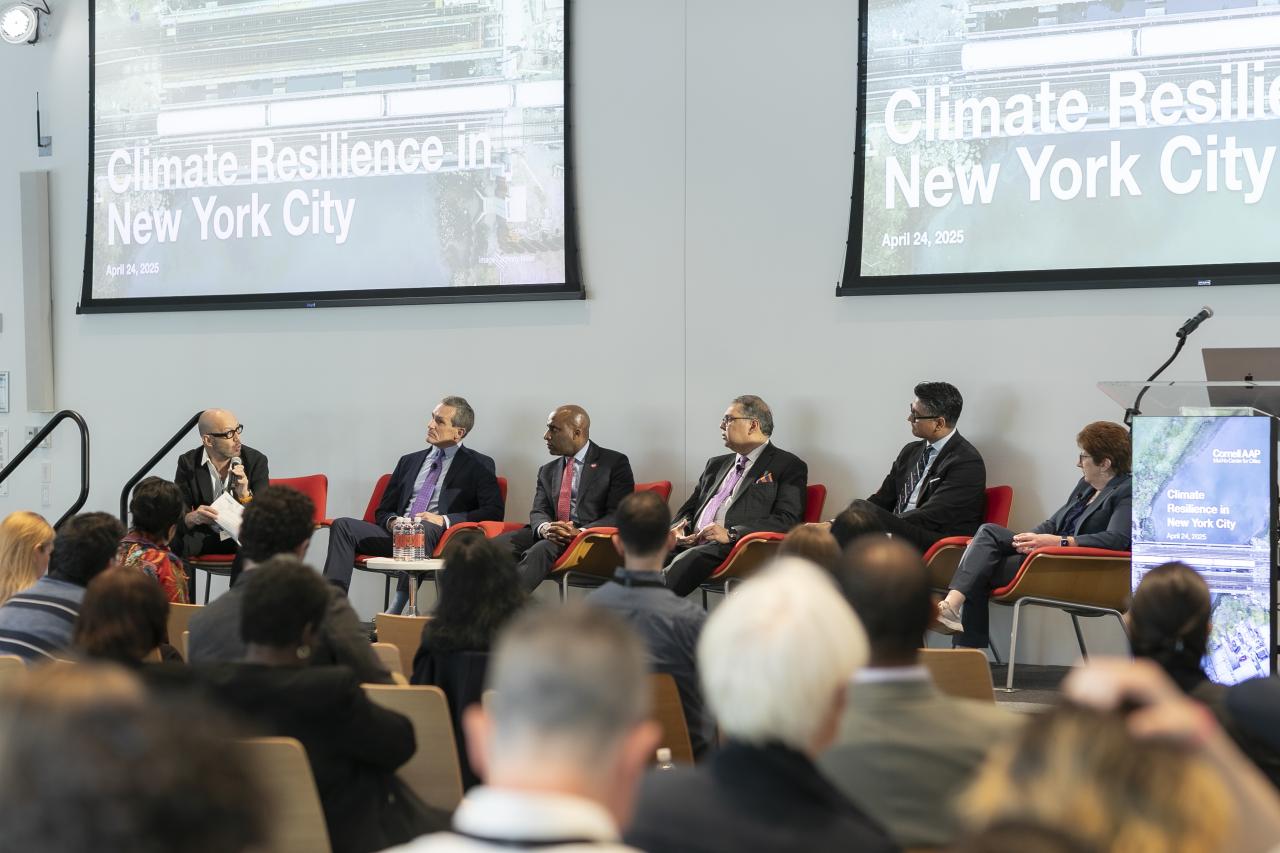 a group of people sitting in chairs in the front of a room filled with spectators