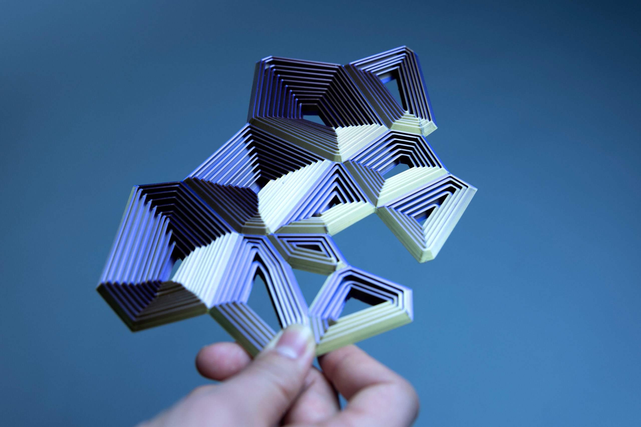 Complex 3D printed structure with a color gradient that goes from purple to golden hue.