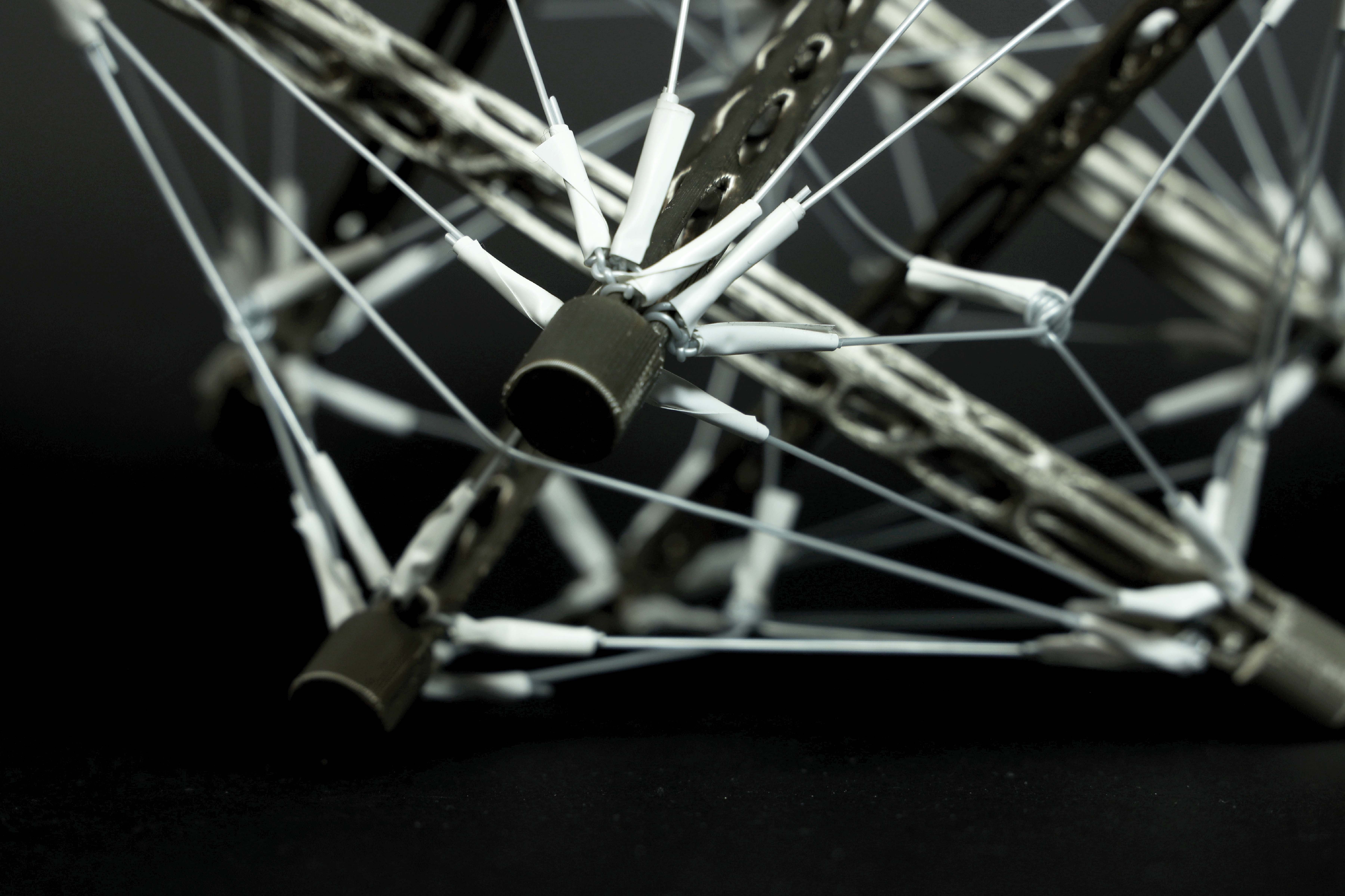 Zoomed-in view of a solid geometric structrure formed by multiple metal rods and wires tensed together.