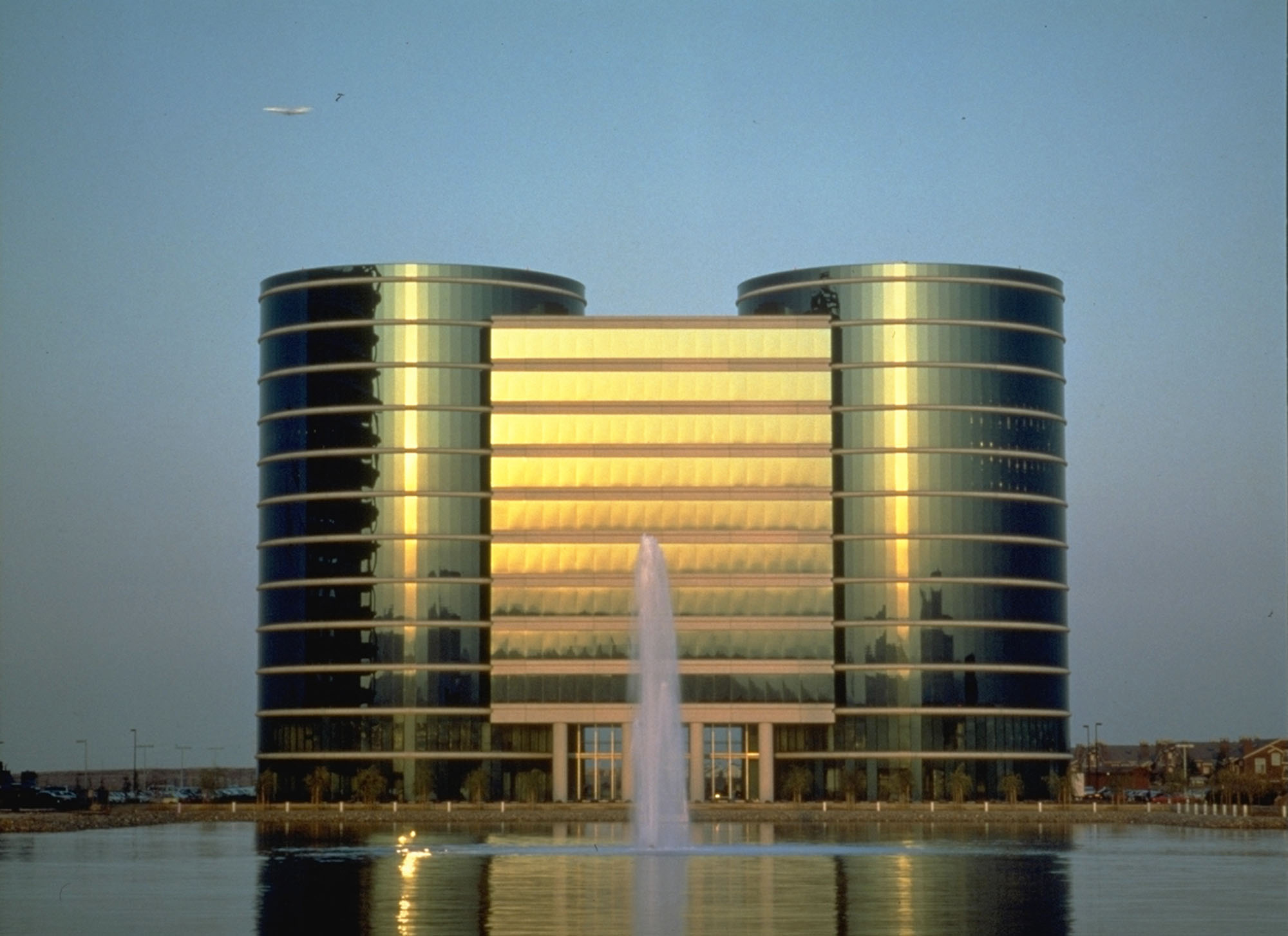 A crisp, rectangular main building joins two pillar-shaped buildings, clad entirely with a reflective exterior.