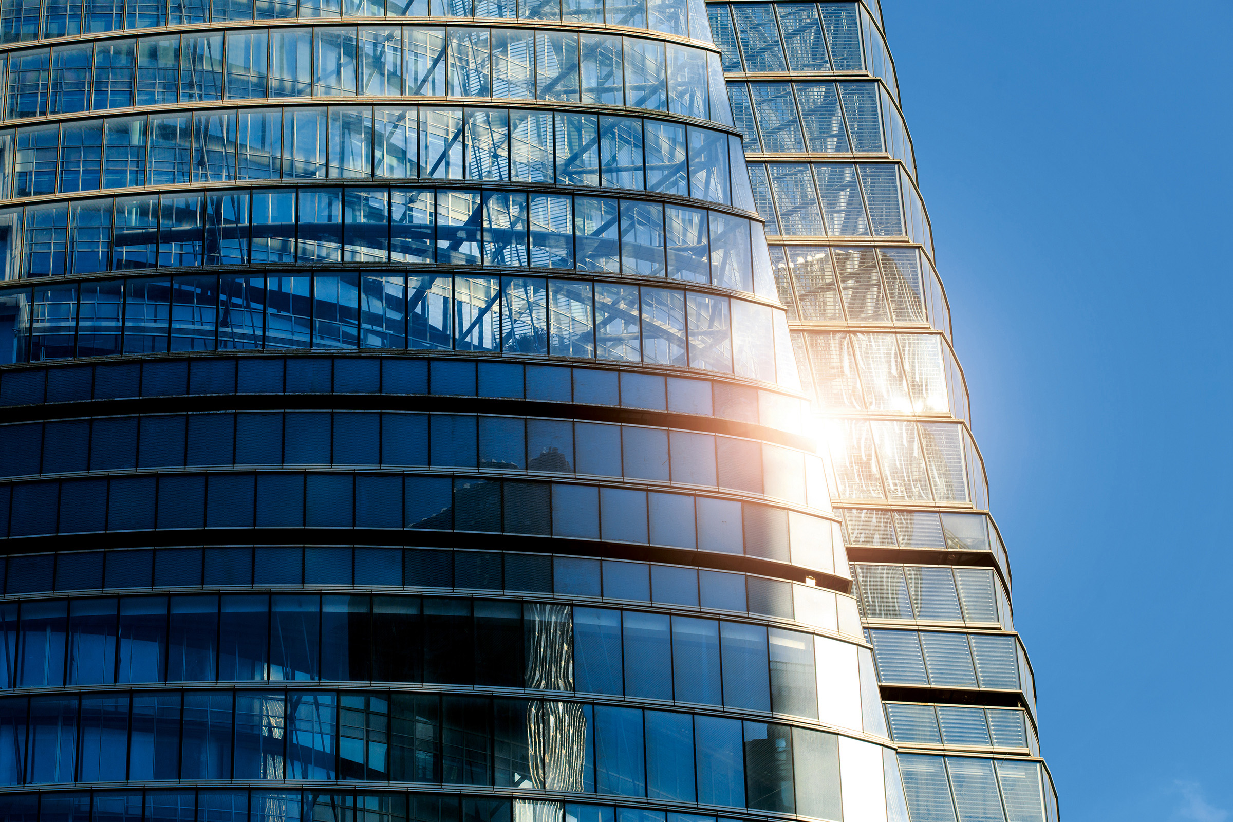 Closeup view of a transparent skyscraper reflecting sunlight.