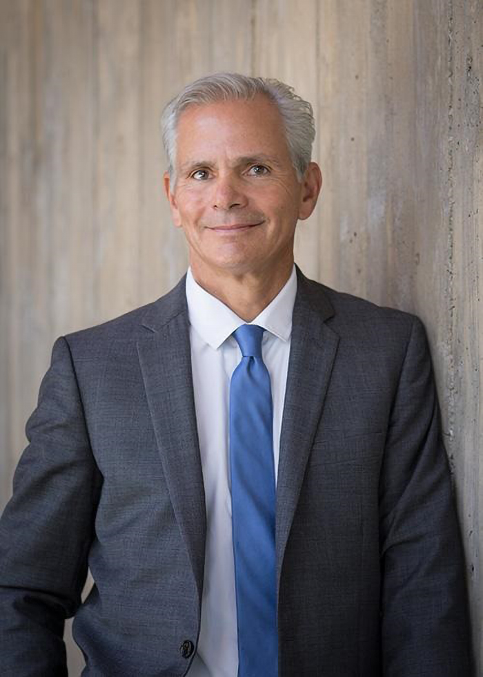 Photo of an older man with gray hair, dressed in a business suit.