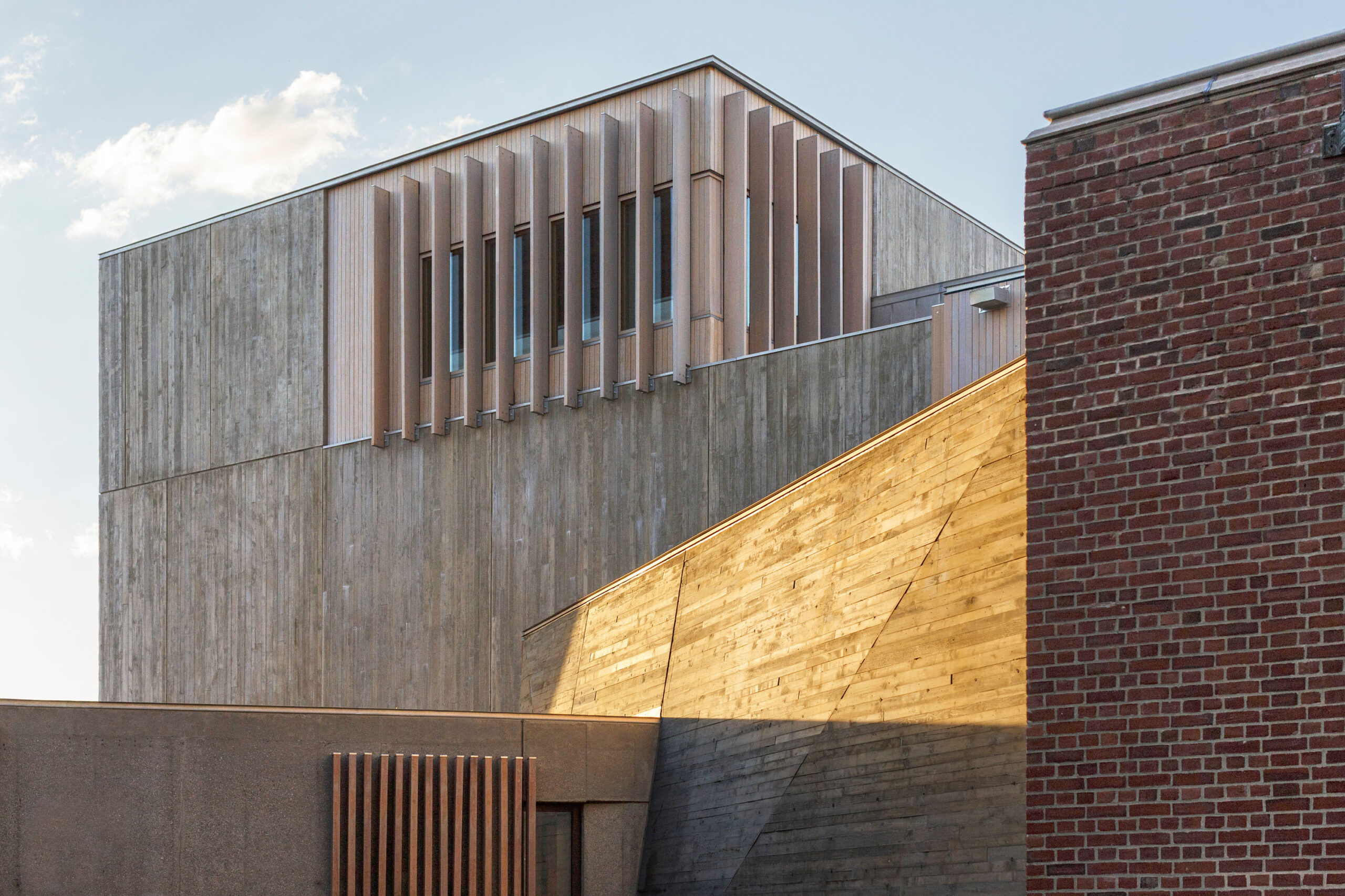 exterior view of a building with long planks installed vertically outside a window at the corner of the building's top floor.