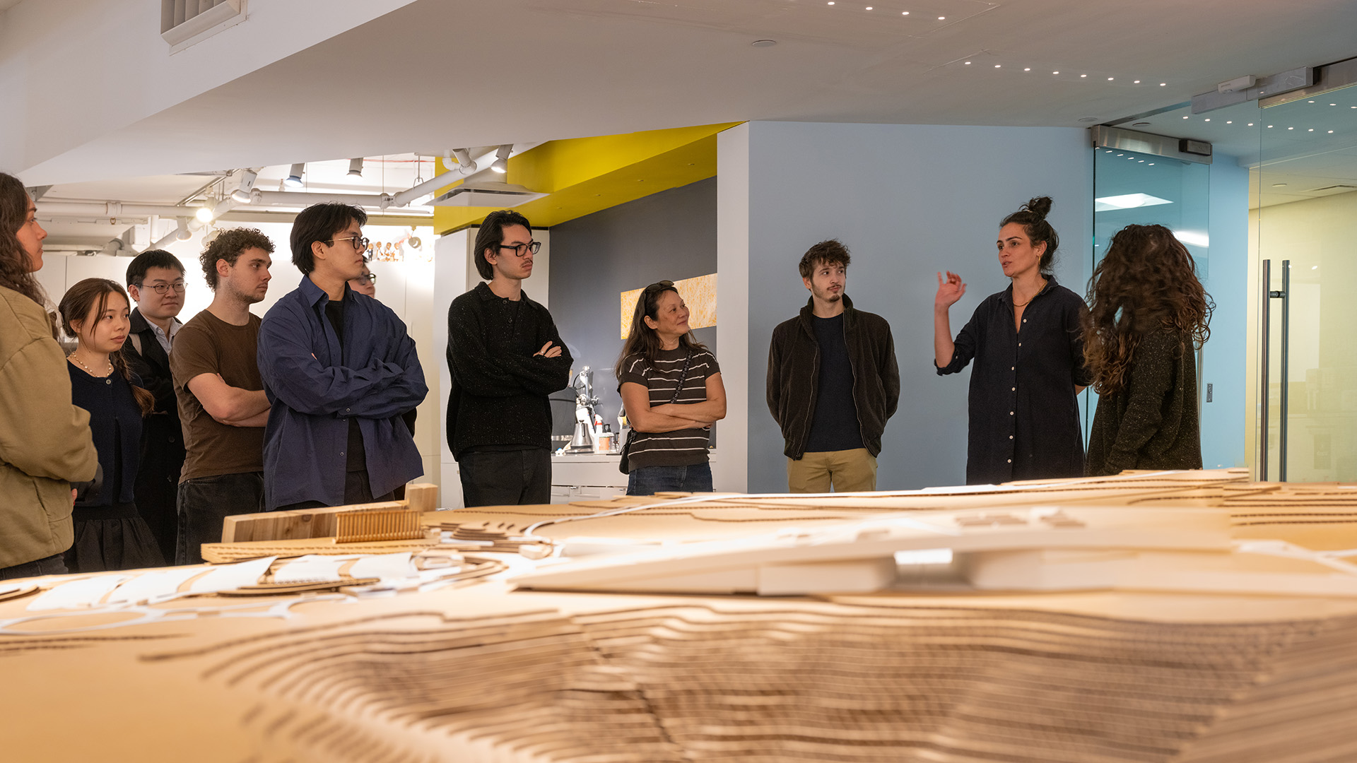People listen to someone talking in front of an architectural model.