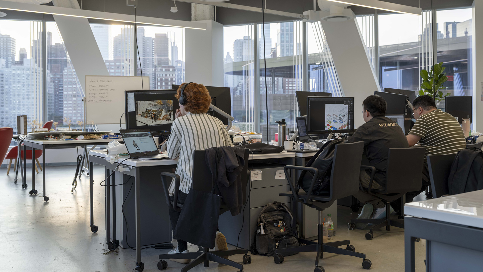 People sit in office chairs in front of computers.
