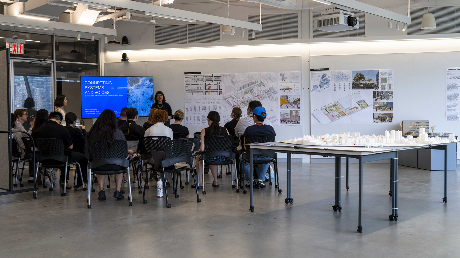 Inside a classroom watching a person give a presentation to a group of seated people.