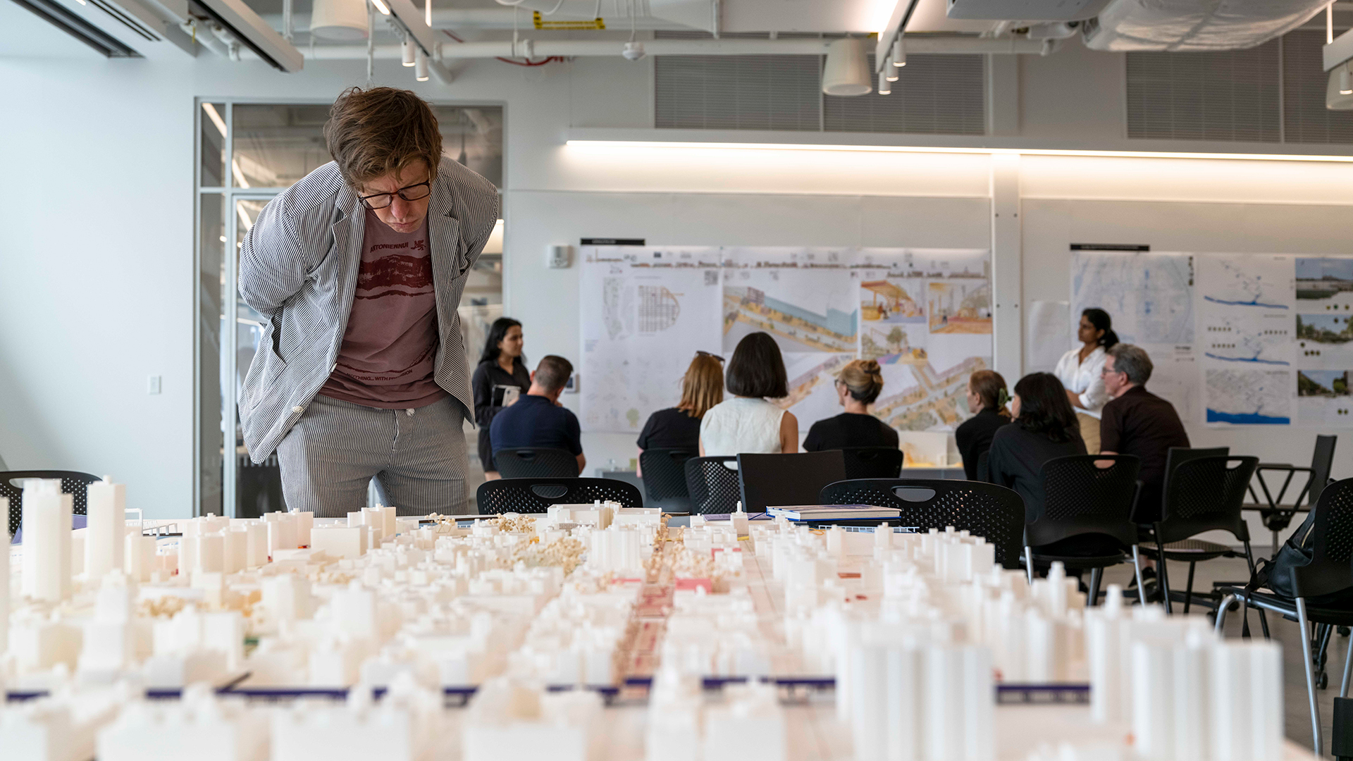 A person looks closely at a large architectural model.