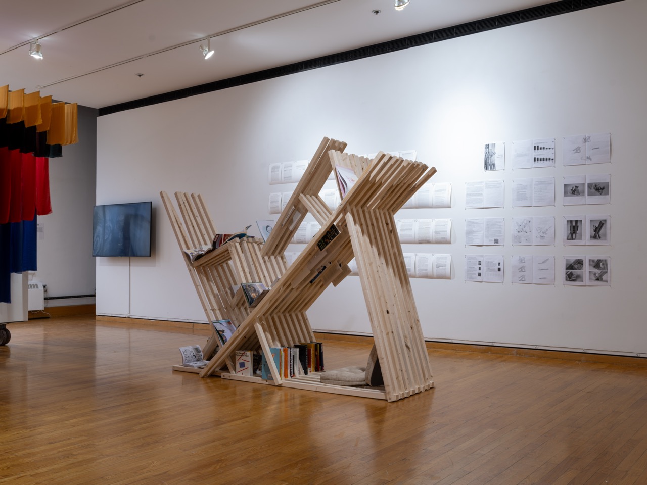 An angular and collapsible book cart holds books with a small seating area inside it.