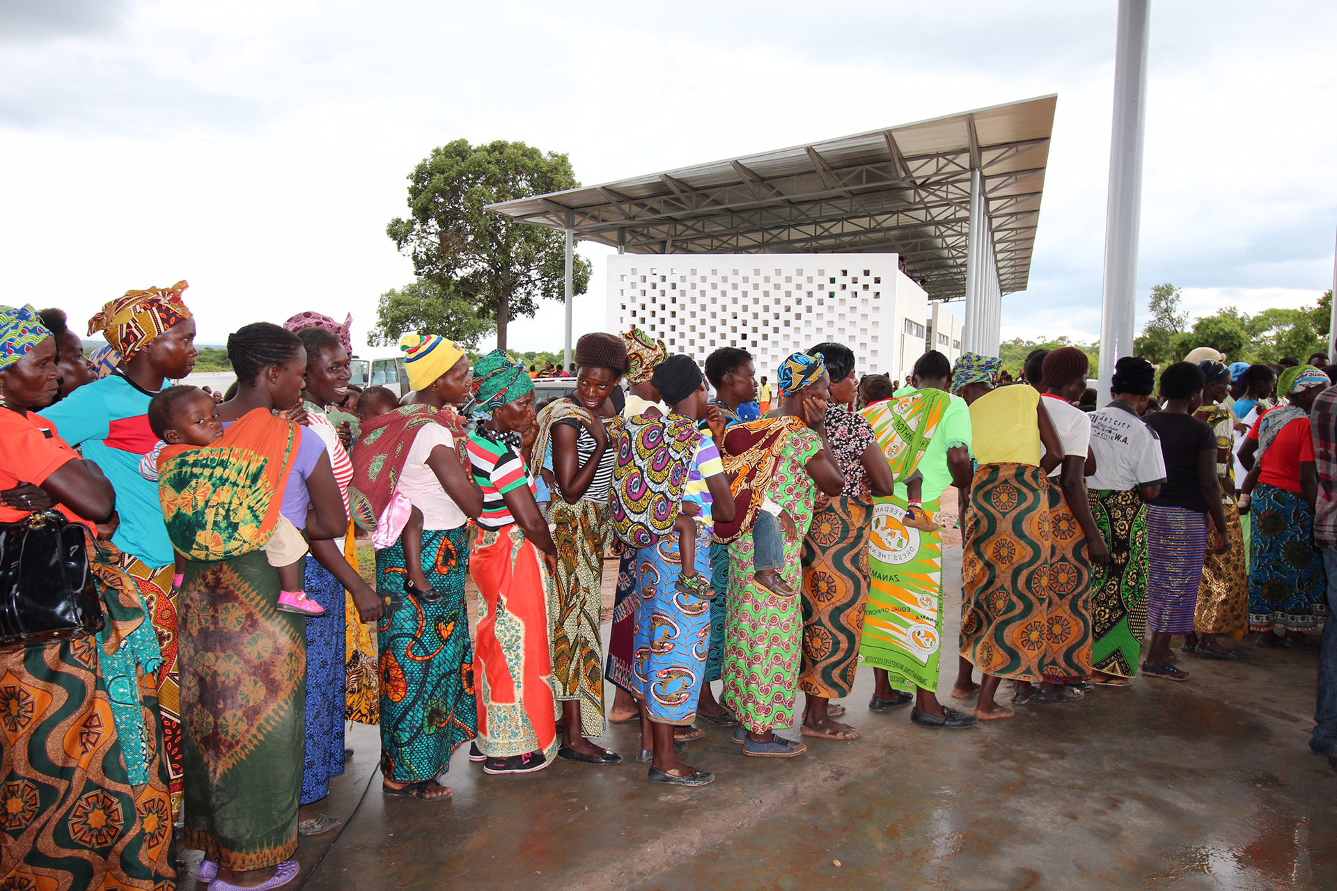 A line of people with colorful outfits waiting outside.