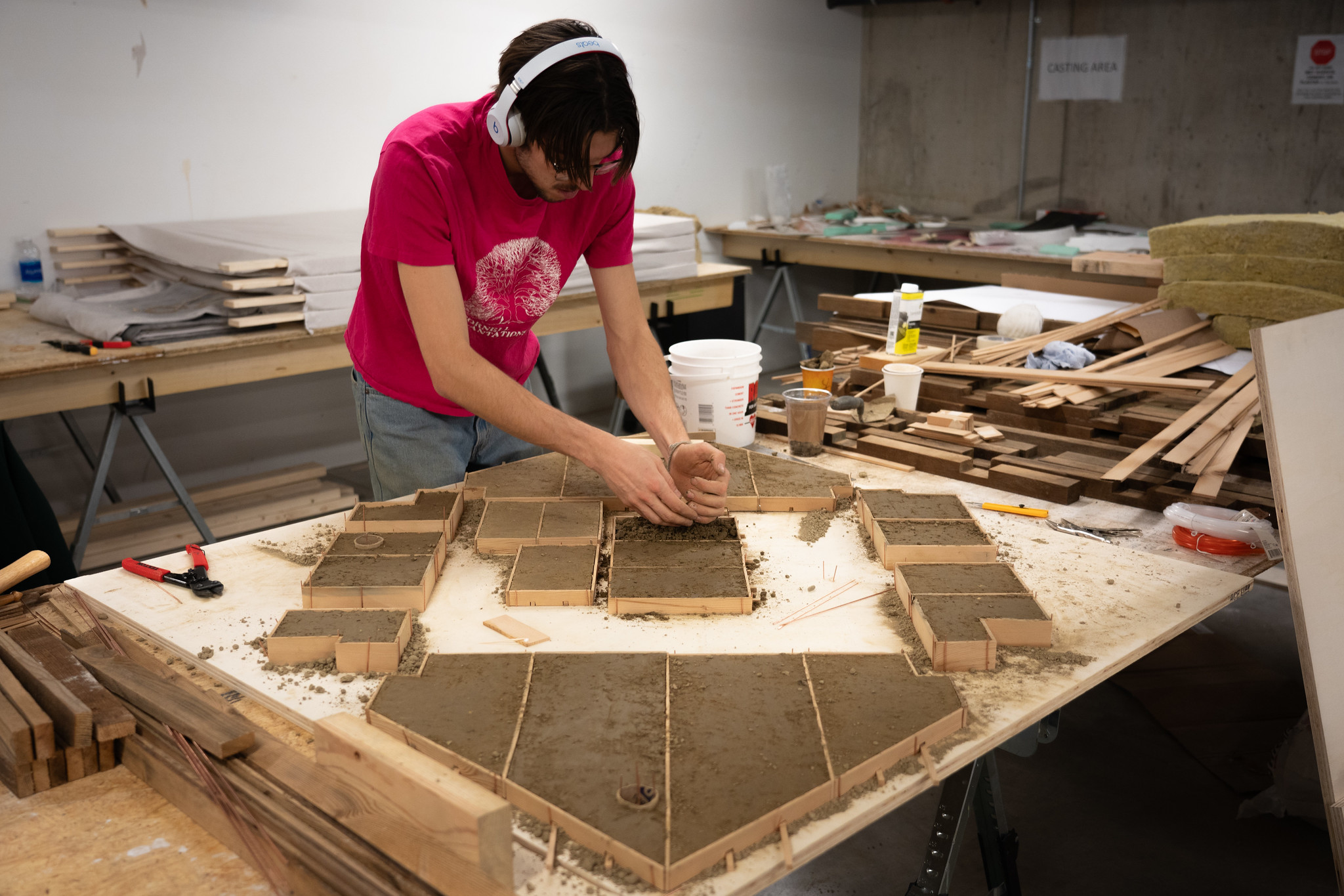 A person files small wooden forms with concrete.