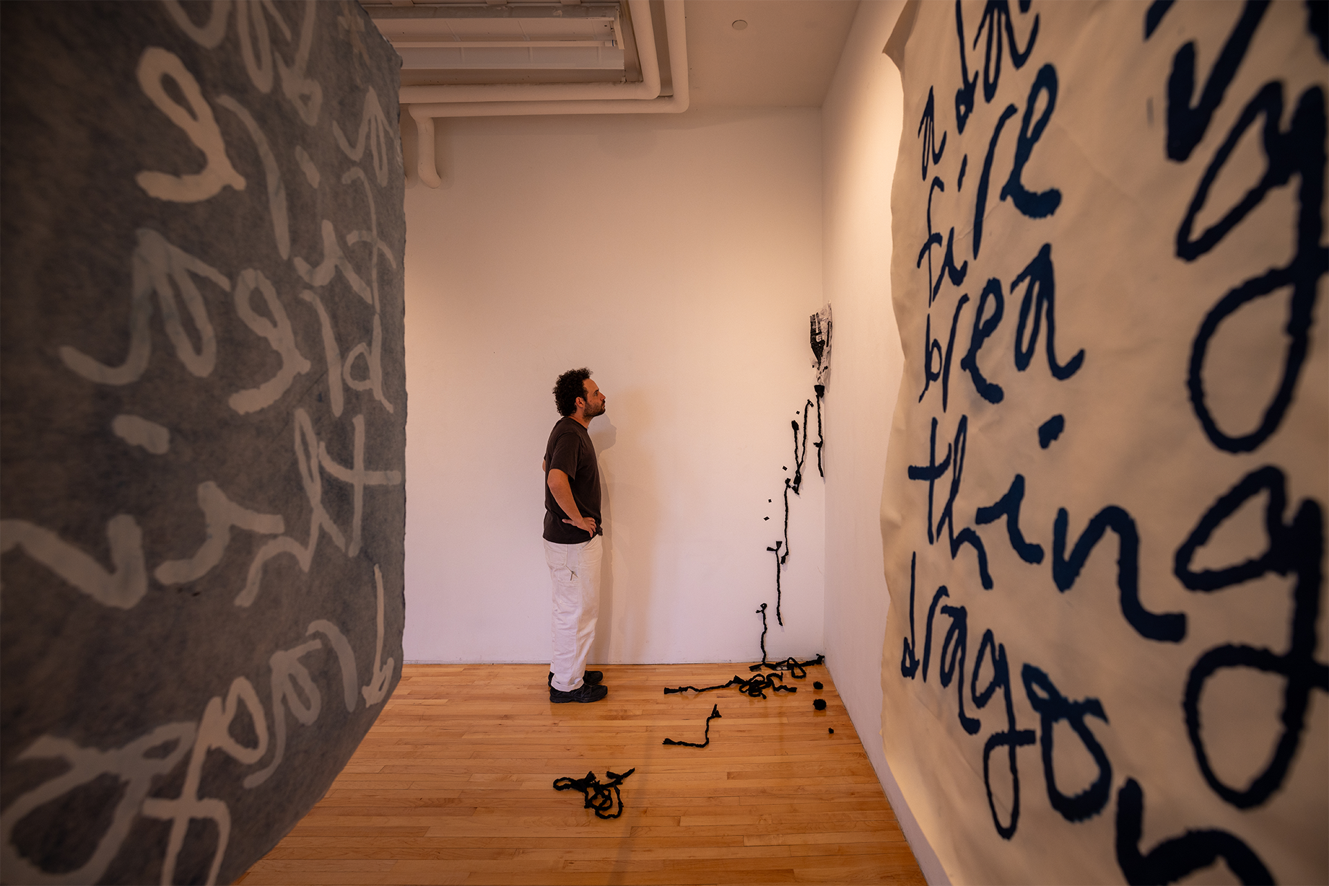 A person observes a fabric sculpture in the corner of a gallery.