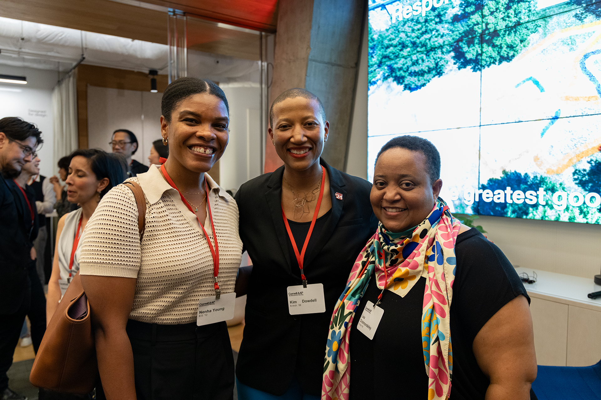 Three people gather for a photo in front of a sign that says 