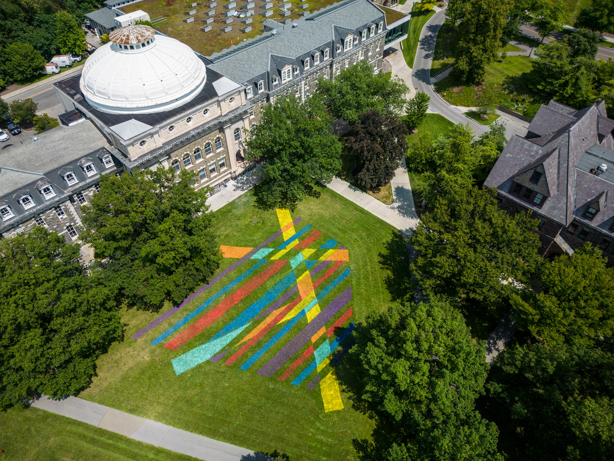 An aerial photo of colorful lines painted on the grass of a college quad.