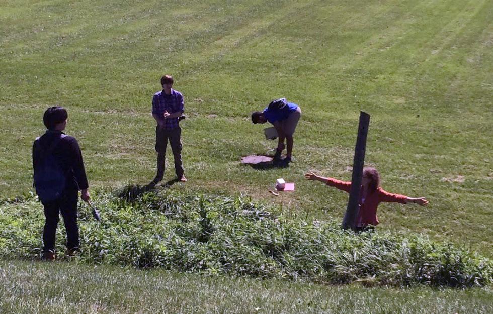 Grass field with four people discussing in a semicircle.