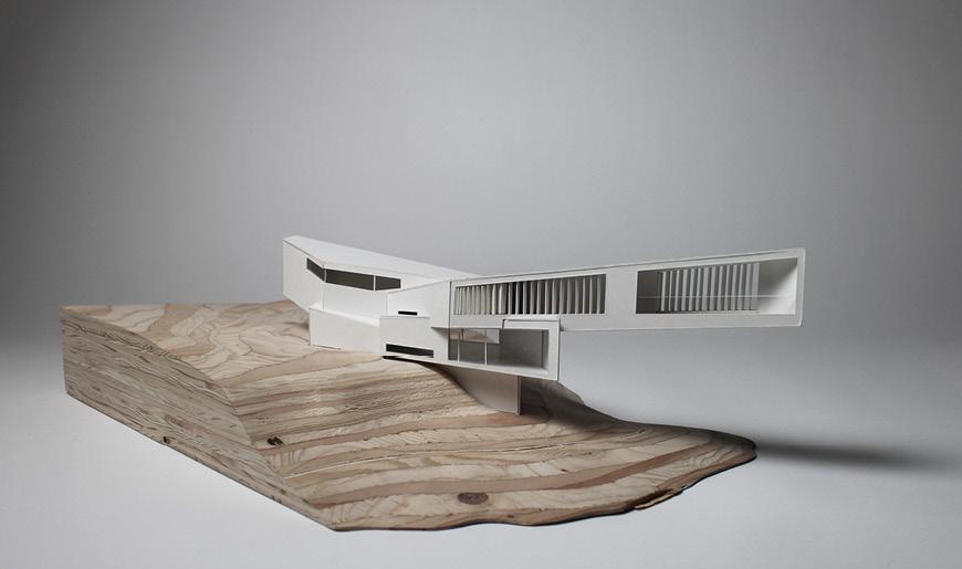 An architectural model with staggered wooden landscapes and an angular white building.