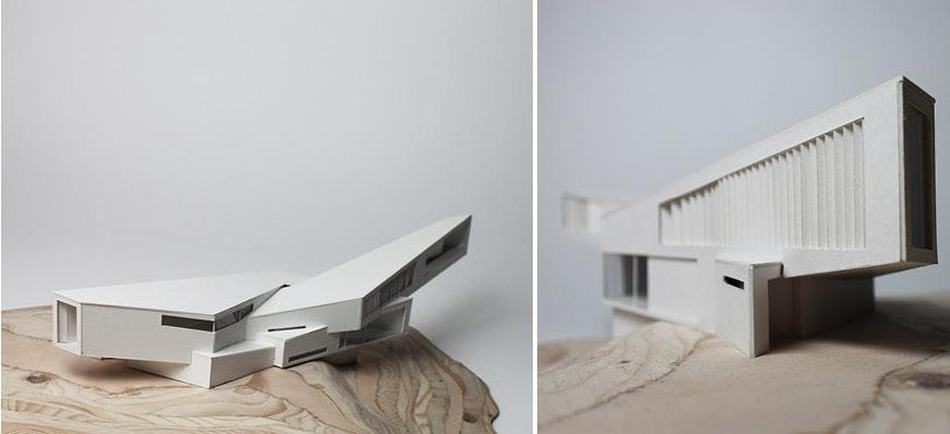 A three dimensional model of an angular building jutting out from a wooden base.