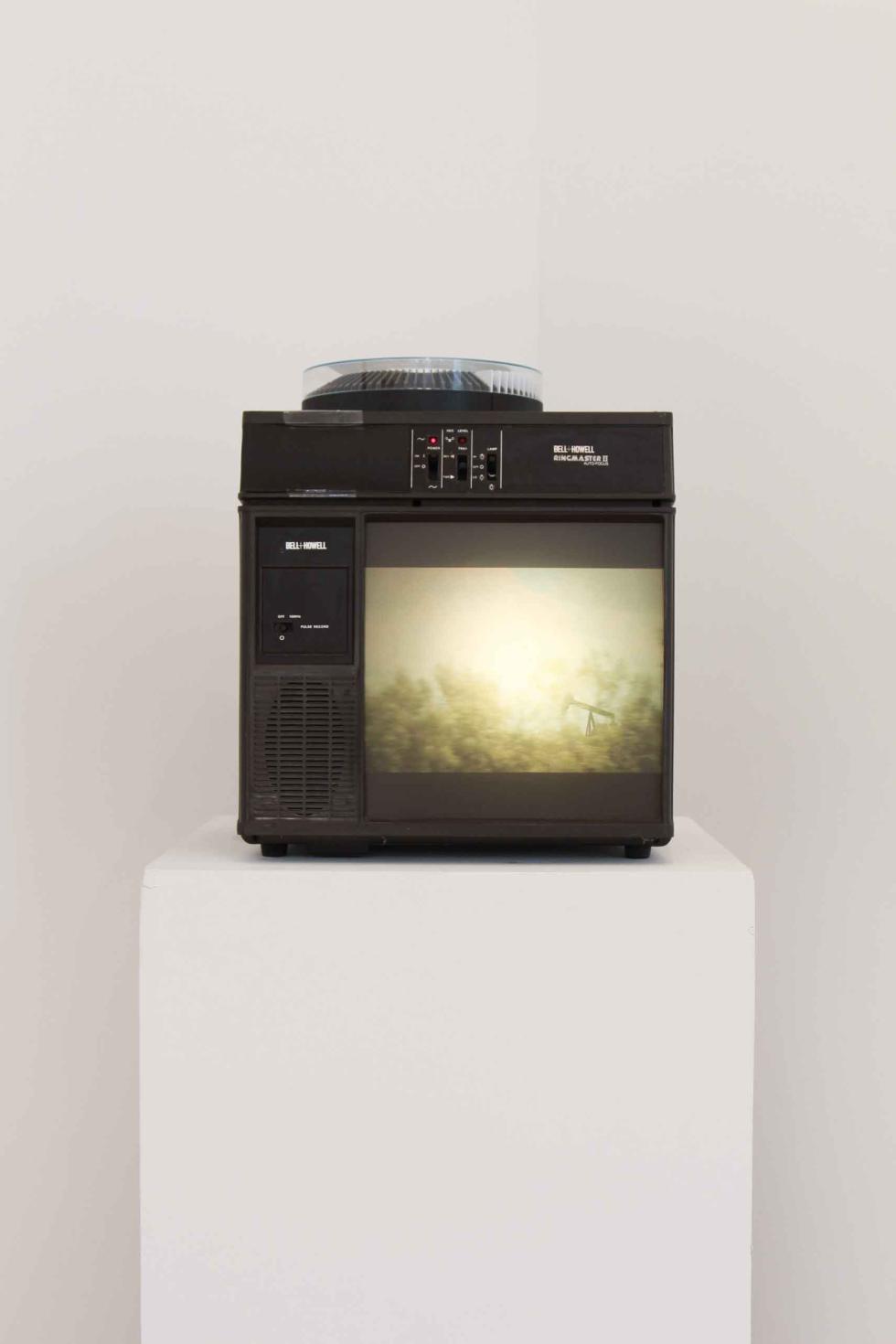 A close up of a projector displaying an image of treetops.