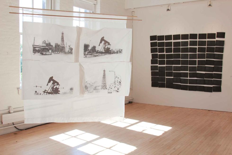 Two hanging fabric sculptures with a grid of black squares on the wall.