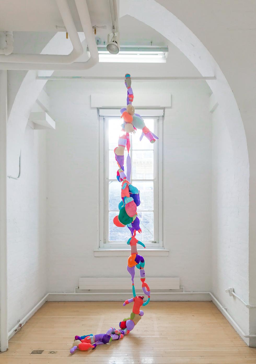 Gallery archway with a hanging fabric sculpture spanning from floor to ceiling.