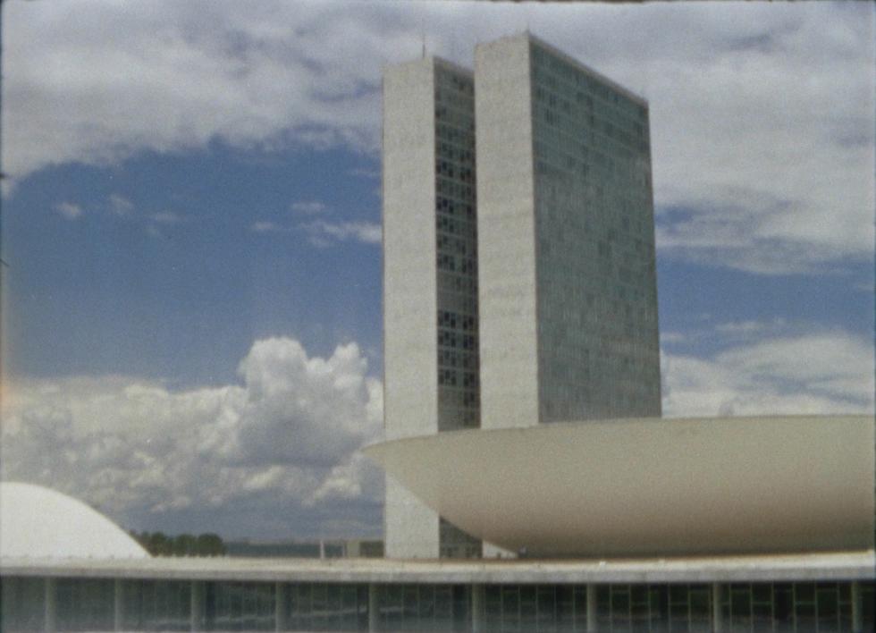 Two gray skyscrapers next to each other with a blue and cloudy sky in the background.