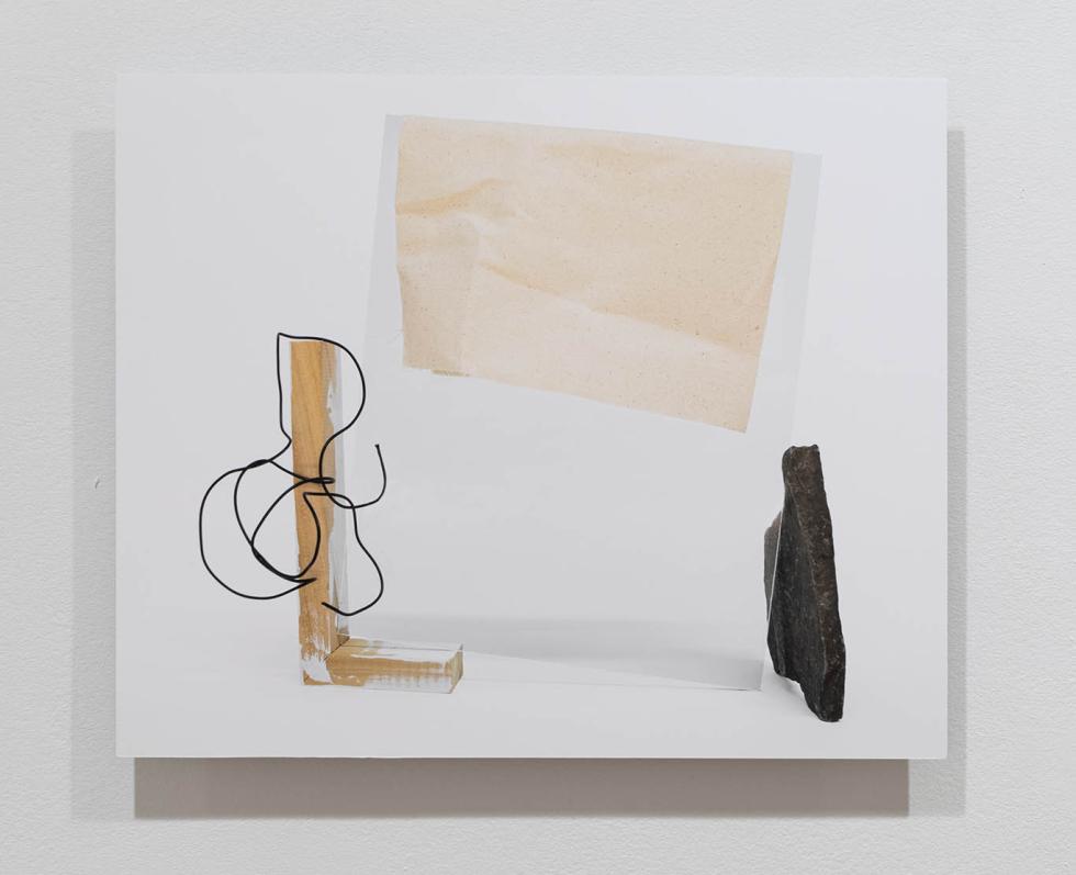 Artistic photograph of mixed media including string, wood, and a rock.