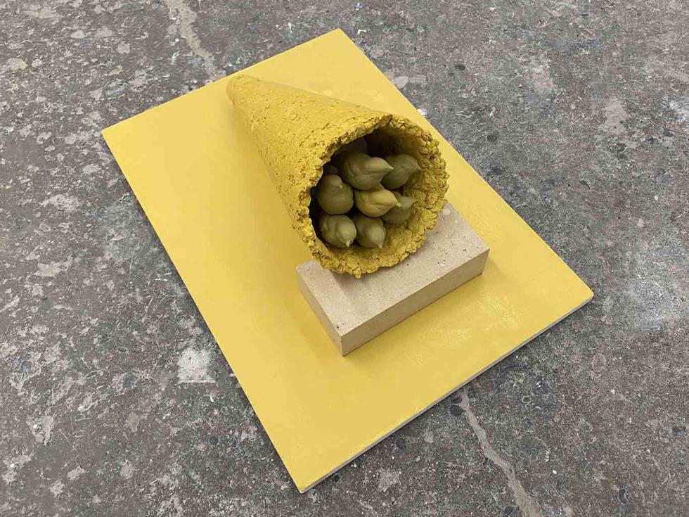 A yellow platform with a yellow cone on its side, with molds of birds inside the cone.