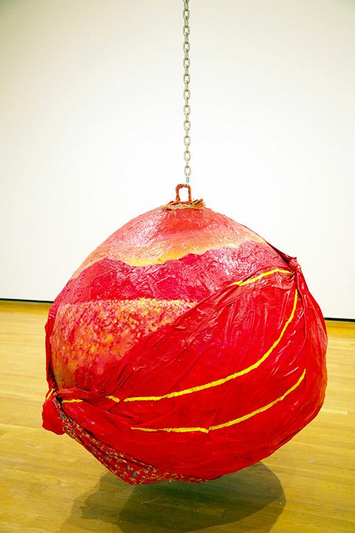 A large red ball hangs from the ceiling by a chain.