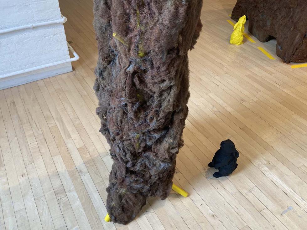 A tall, large, brown sculpture with a small brown bunny looking up at it.