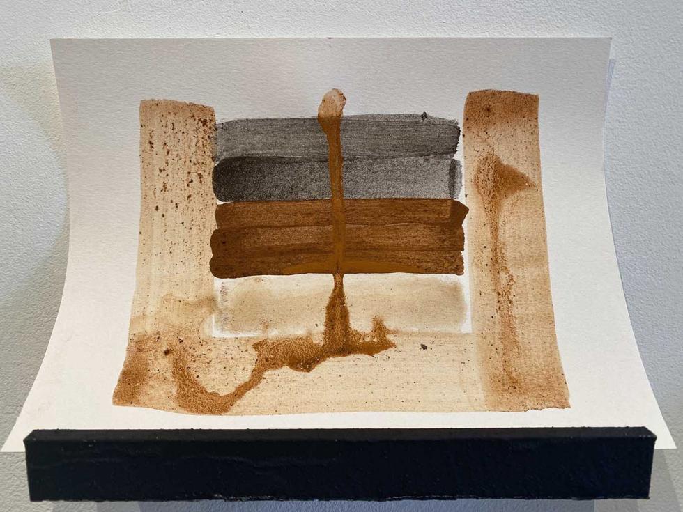 A small shelf with an ink painting in shades of brown.