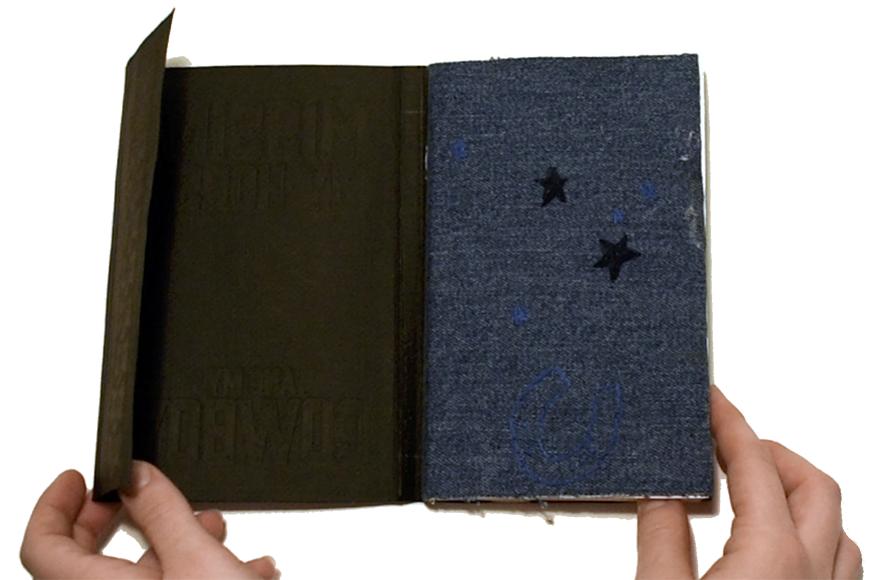 Person holds an open book that has a page of denim with two stars.