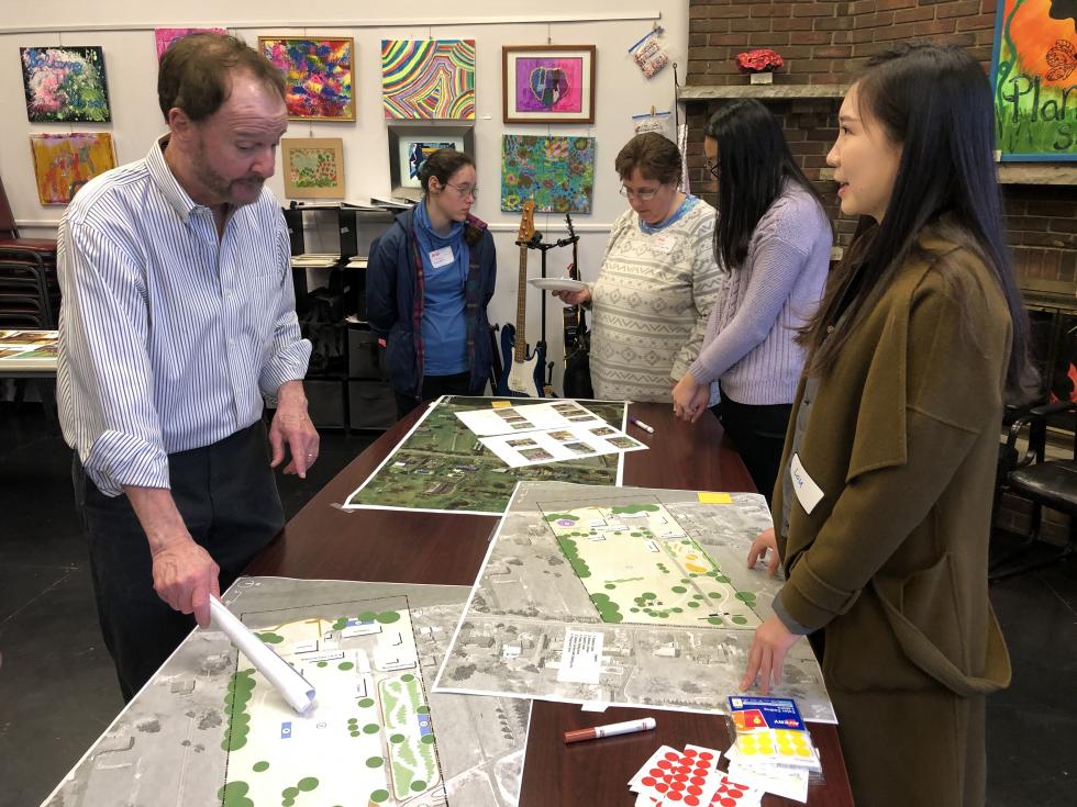 People gathered around a table with maps on the table.