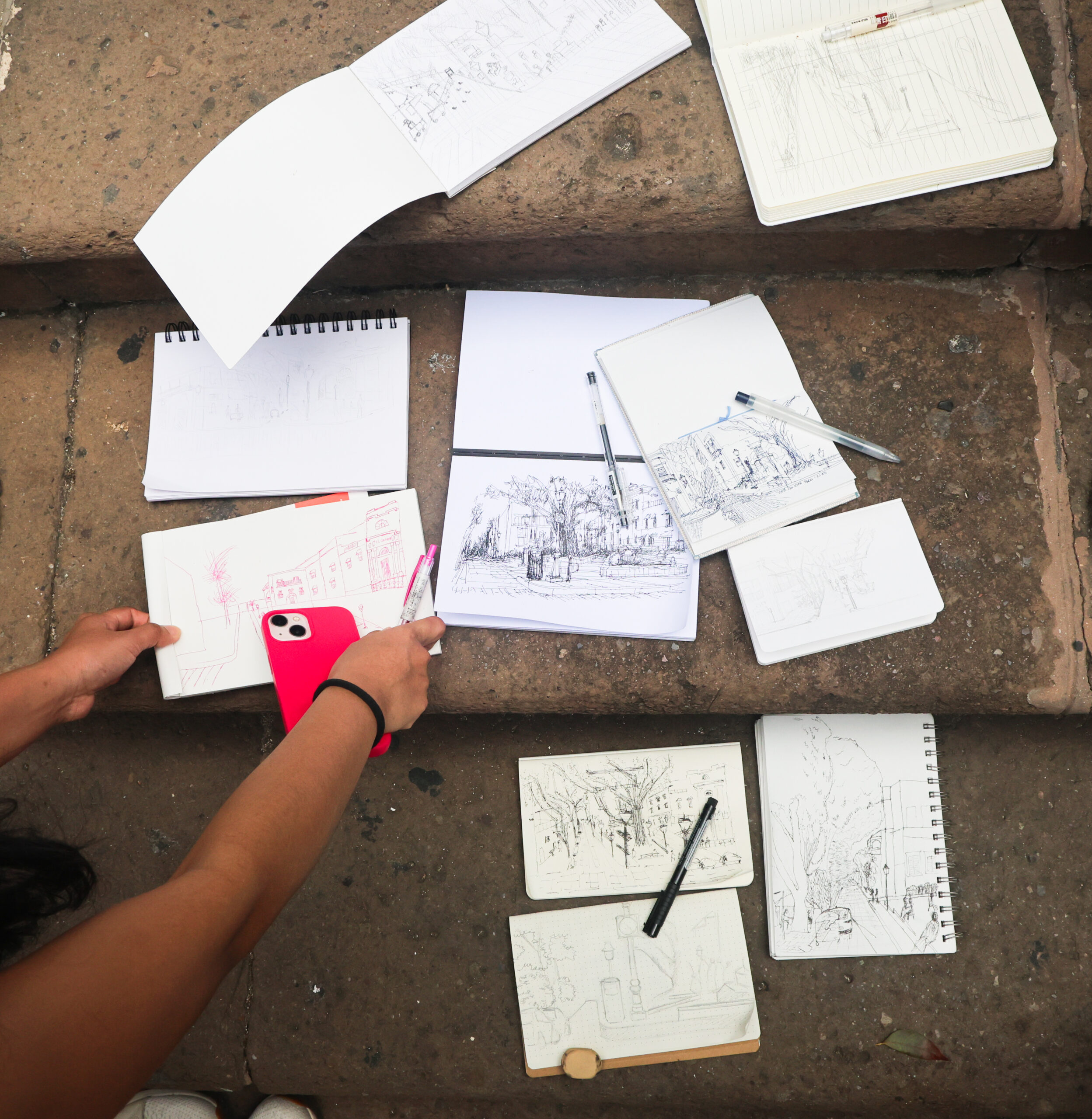 A person points to drawings scattered on a set of stone stairs.