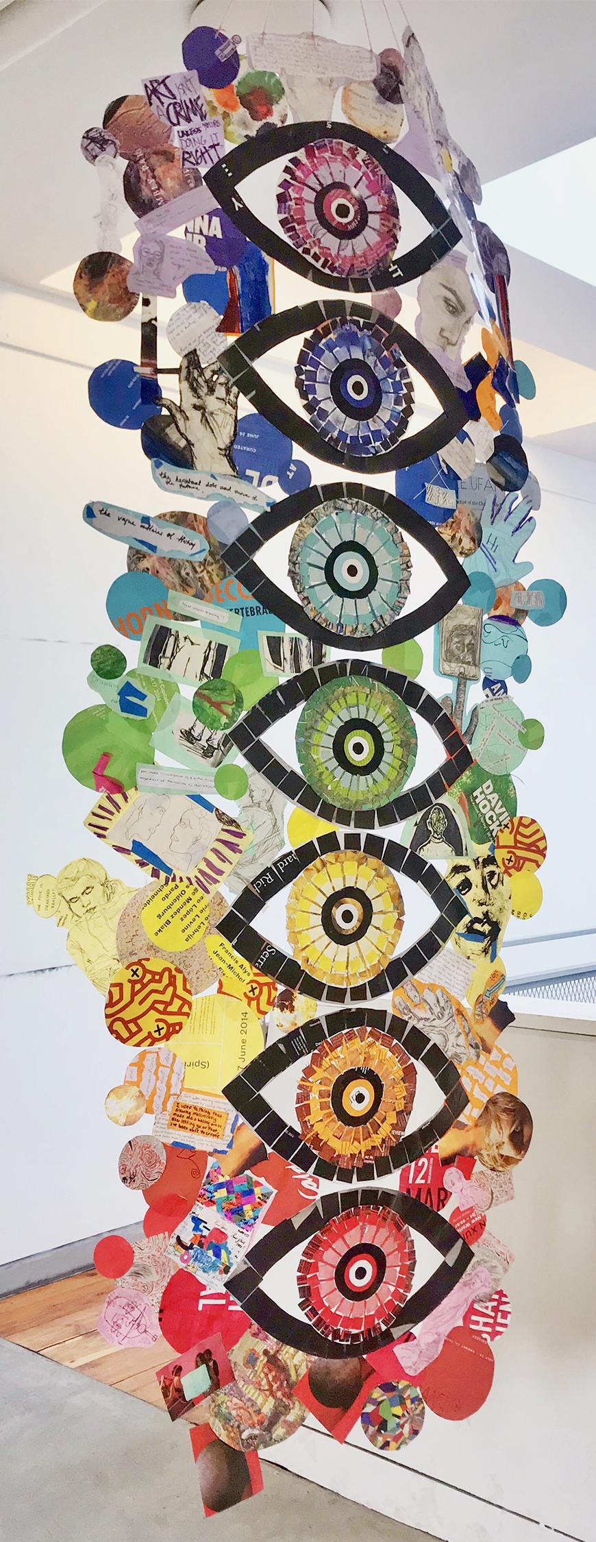 Series of paper cutouts of abstract eyes stacked into a sculpture.