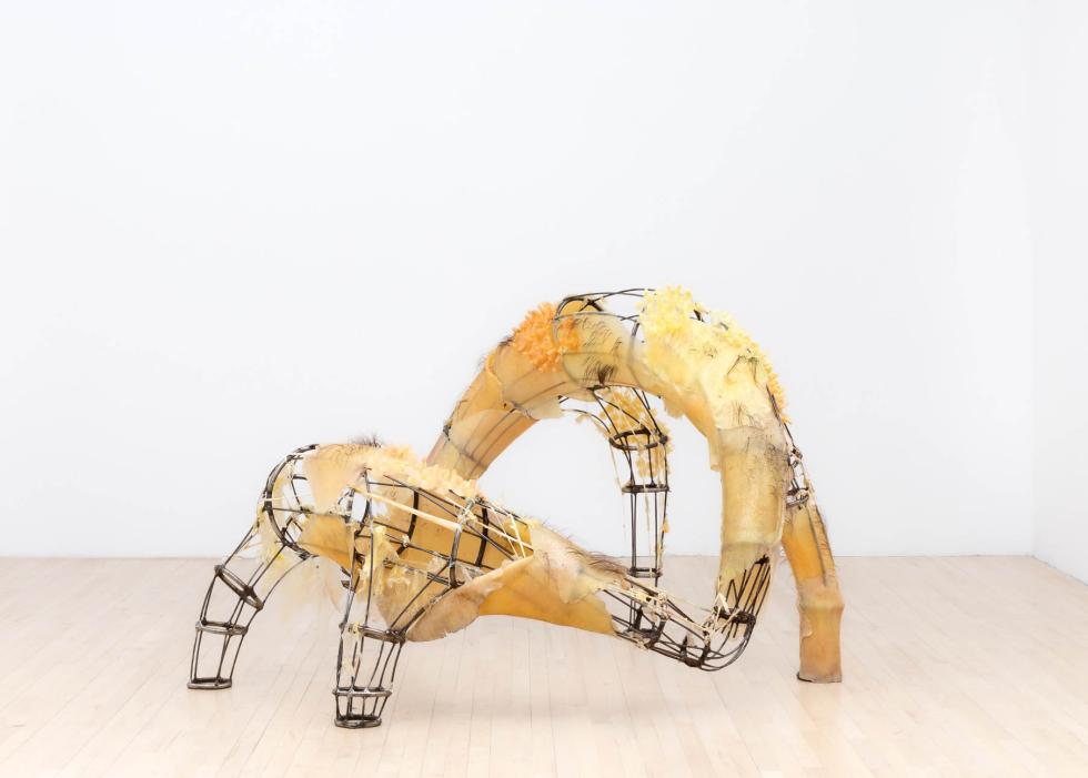 A multi-legged metal sculpture with silicone slabs attached to parts of it.