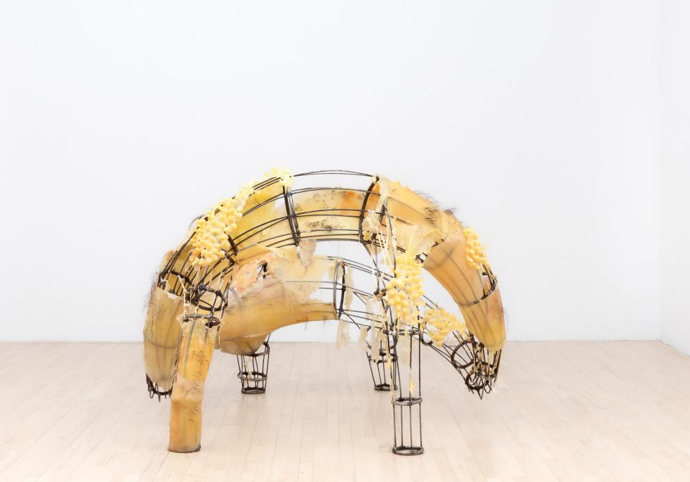 A multi-legged metal sculpture with silicone slabs attached to parts of it.