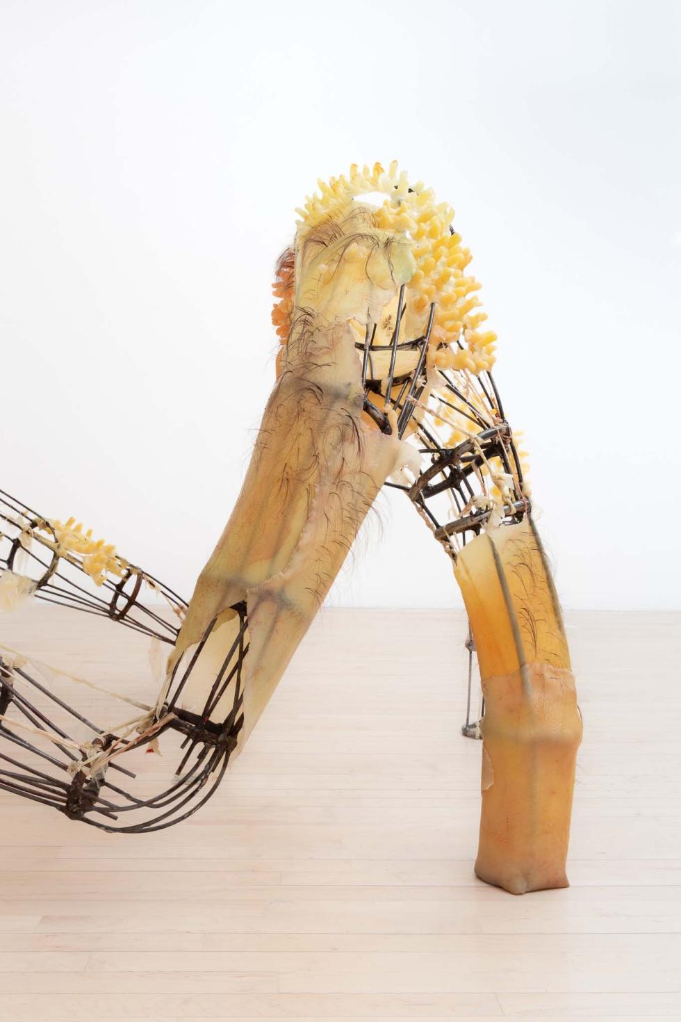 A multi-legged metal sculpture with silicone slabs attached to parts of it.