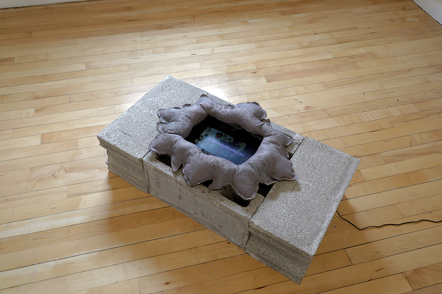 Cinder blocks with a sculpture on top, with a video screen inside.