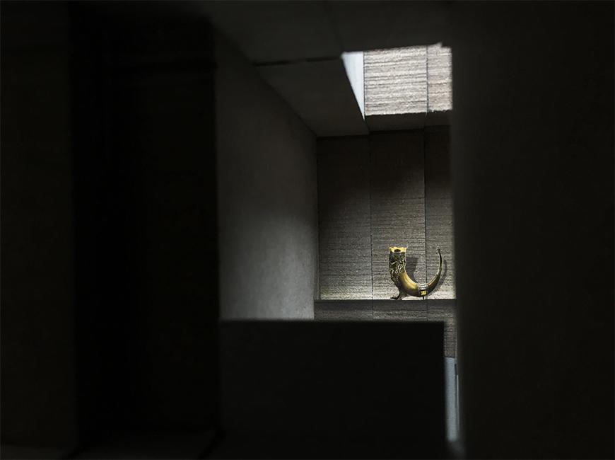 Interior view of an architectural model with an object illuminated by a skylight.
