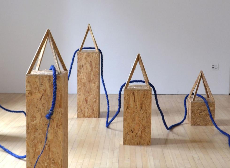 A series of plywood sculptures that are connected with a thick rope.