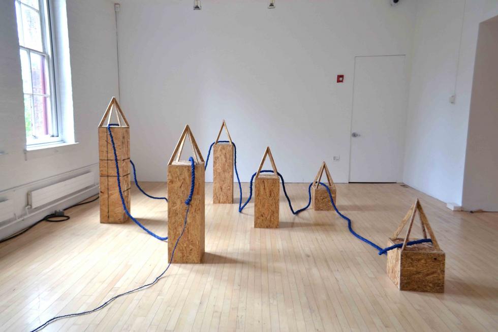 A series of plywood sculptures that are connected with a thick rope.