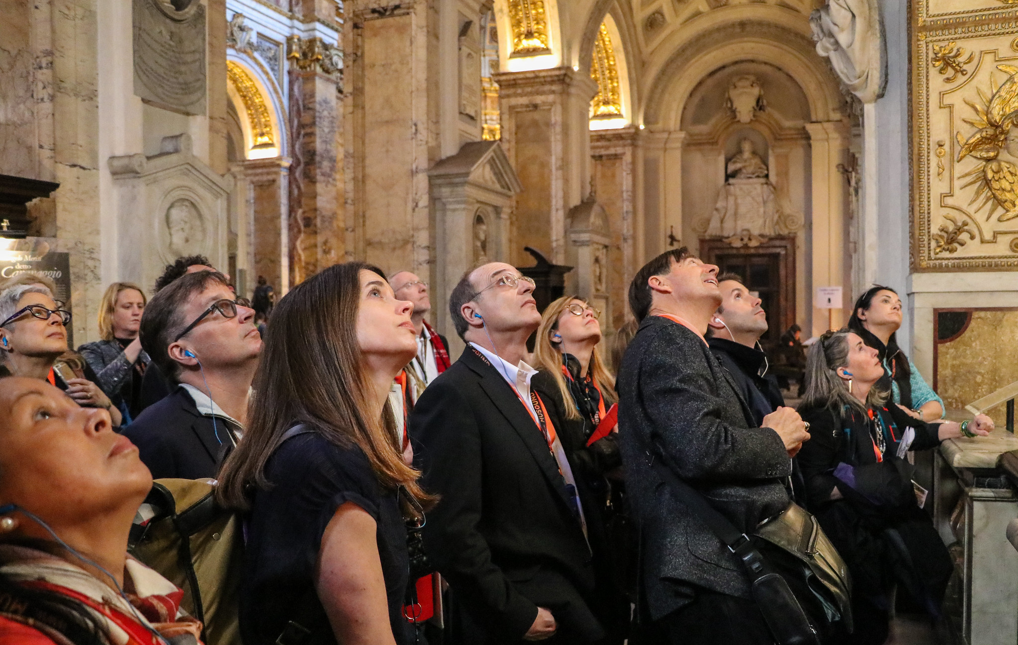 A group of people inside a building look upward.