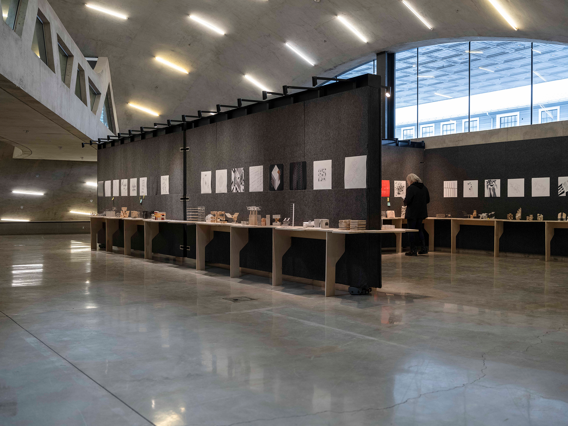 Interior of a concrete dome building with architectural models and drawings lining the walls.